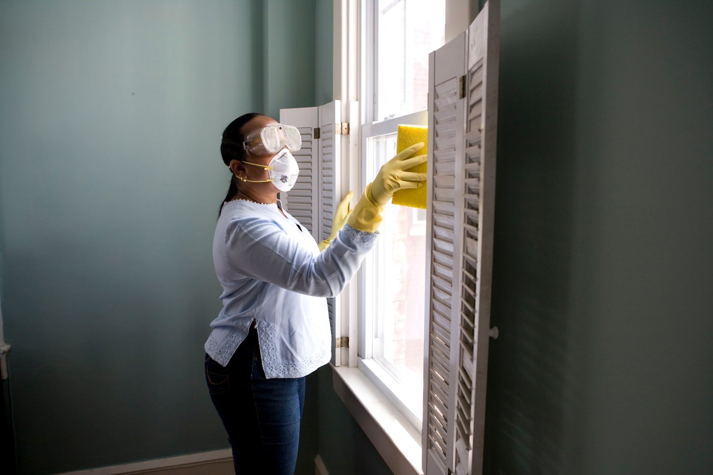 Sylwia's team cleaning a window carefully wearing gloves and a mask